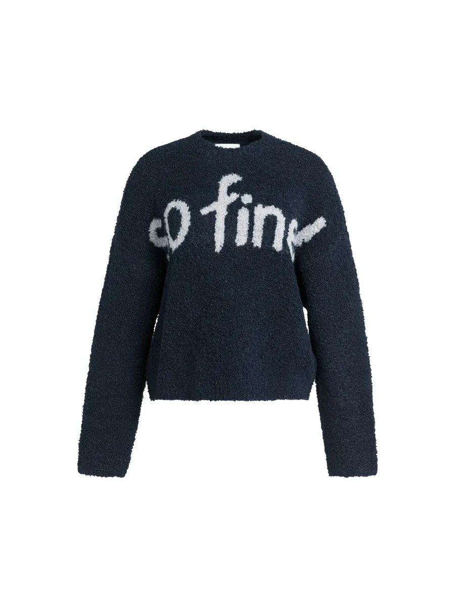 Frau im dunkelblauen Bouclé-Pullover mit Schriftzug so fine